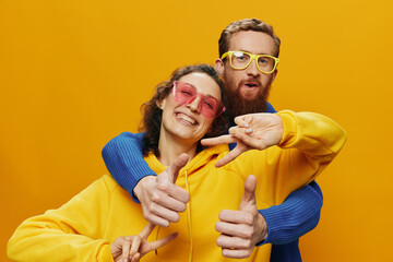 Man and woman couple smiling cheerfully and crooked with glasses, on yellow background, symbols...