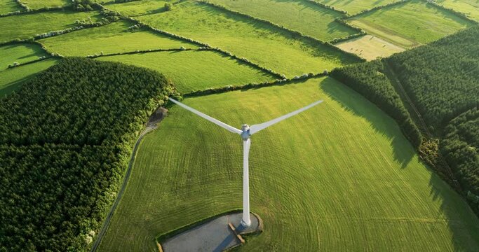 Large wind mill with blades on green field aerial view of green valley sunset 4k