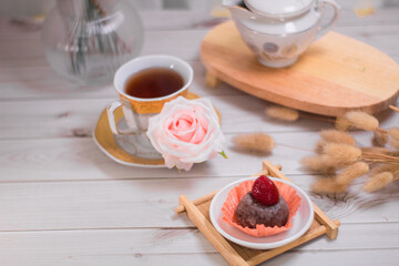 Chocolate mochi balls, Japanese dessert chocolate mochi or glutinous rice ball with strawberry topped. served on white plate, cup of tea and rattan tray.