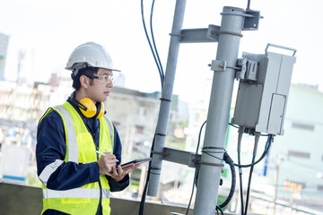 Building inspector man using digital tablet while checking telecommunication pole or telecom tower....