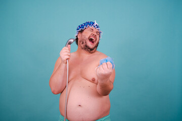 Funny fat man is washing himself in the shower. - obrazy, fototapety, plakaty