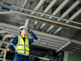 Asian man inspection engineer holding his safety helmet while looking at plumber piping system....