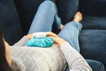 Woman had a stomach ache menstrual pain and gastritis inflammatory bowel disease gives a hot water bag to compress to alleviate the illness and reduce. She put hand on her stomach - obrazy, fototapety, plakaty