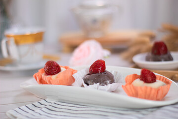 Close up of Japanese dessert chocolate and strawberry mochi or glutinous rice ball with strawberry topped. served on white plate and cup of tea. blurred background