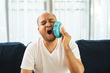 Young asian man is sick has a fever is hot has a cold body aches gives a hot and cold water bag to compress to alleviate the illness and reduce fever.