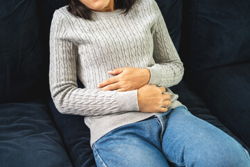 Woman had a stomach ache menstrual pain and gastritis inflammatory bowel disease. She put hand on his stomach and squeezed it to relax and soothe has go to toilet need to poop - obrazy, fototapety, plakaty