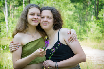 Two girlfriends are standing in the forest in summer.