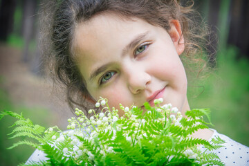Spring in the forest little girl holding a bouquet of lilies of the valley.