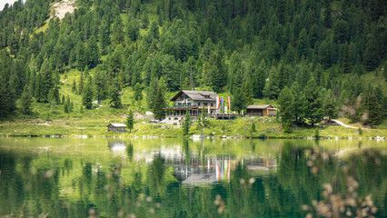 Fototapeta na wymiar Österreichisch aussehendes Haus an einem klaren See mit einer Spiegelung im Wasser. Bäume im Hintergrund.
