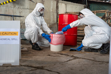 A team of two chemists, wearing PPE suits and gas masks, recover a deadly chemical spill on the...