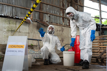 A team of two chemists, wearing PPE suits and gas masks, recover a deadly chemical spill on the...