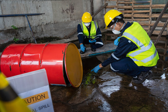 Two officers wearing gas masks inspected the area of a chemical leak in an industrial warehouse to assess the damage. Technicians wearing gas masks inspect and assess the recovery of toxic spills..
