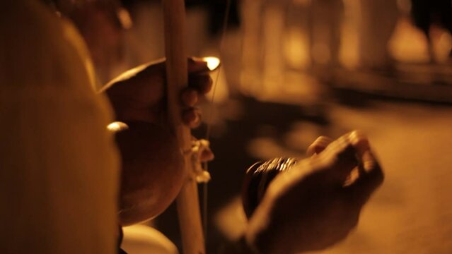 detail of hands playing berimbau, capoeira instrument