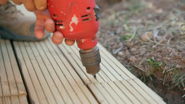 Male builder using drill to unscrew the screws off the timber	