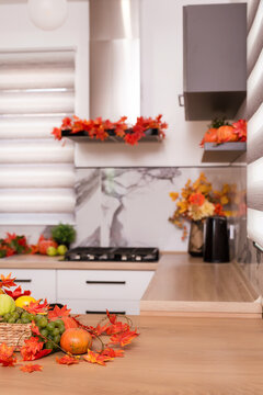 Autumn kitchen interior. Red and yellow leaves and flowers in the vase and pumpkin on light background. Vertical image