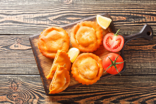 Tielle Setoise is a Octopus and Tomato pies from Sete closeup on a wooden board on the table. Horizontal top view from above