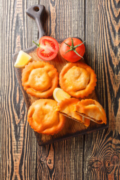 French closed pie tielle with seafood and vegetables close-up on a wooden board on the table. Vertical top view from above
