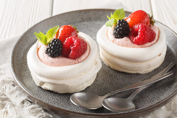 Anna Pavlova meringue cakes with cream and fresh summer berry closeup on a plate on the wooden table. Horizontal