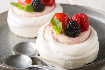 Tasty Pavlova meringue cakes with fresh berries on a plate on the wooden table. Horizontal