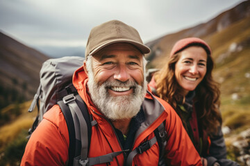 Two senior hikers wearing casual clothes admiring a scenic view from a mountain top. Adventurous old man and lady with backpacks. Hiking and trekking on a nature trail.