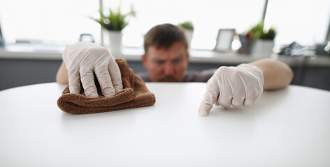 Close-up of cleaning male workers hands swiping dust of company workplace. Serious man wearing...