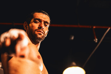 Boxing fighter shirtless posing, caucasian boxer punch his bare fist and wrap in front of camera,...
