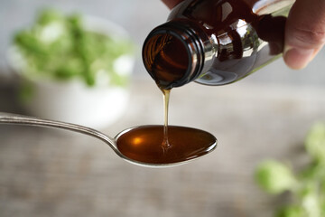 Coleus amboinicus syrup being poured onto a spoon
