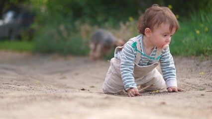 baby girl playing in the sand outdoors in the park learning to take her first steps. happy family kid dream concept. baby toddler plays in the sand with a stick from a tree lifestyle