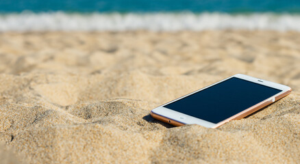 latest technology cell phone buried on the beach during summer day in high resolution