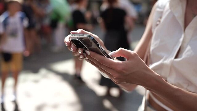A girl on the street in her hands holds a black iPhone 14 pro max close-up.