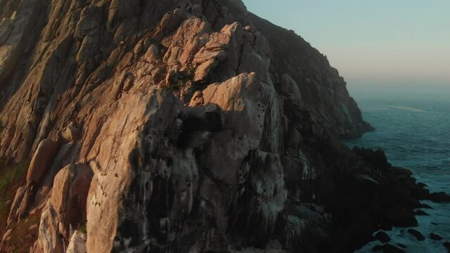 Drone circling around huge rock in the ocean in morro bay