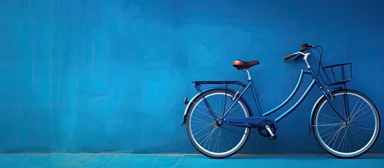 Deurstickers Fiets A high-quality photo of a bicycle is positioned against a blue wall, with empty space available