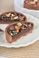 freshly handmade beautiful France rocher dark chocolate layer tart w mixed macadamia peanuts on white marble luxury background with bamboo decoration halal food dessert menu for cafe