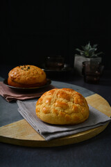 freshly handmade baked Macau crispy round polo bun bread w red bean paste on dark black luxury background with ceramic decoration halal food dessert menu for cafe