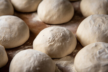 Fototapeta na wymiar Raw dough balls and flour on wooden background, top view