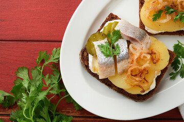 Open sandwich or smorrebrod with rye bread, herring, eggs, caramelized onions, parsley and cottage cheese on old wooden rustic table backgrounds. Danish or Scandinavian traditional food snack lunch.