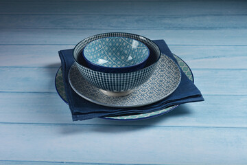 traditional luxury utensil dine ware Japanese ceramic china blue art drawing sakura flower design round big small gloss plate bowl w cloth and chopstick on blue wood table background