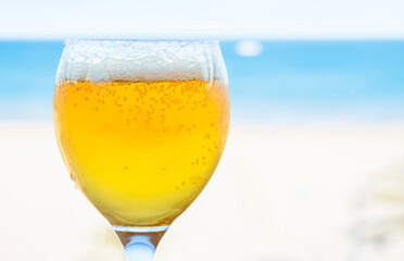 Glass of beer on a blurred blue background of a sea. Copy space. Shallow depth of field