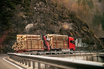 Switzerland, Europe 03.05.2023: Loading logs onto a logging truck. Portable crane on a logging...