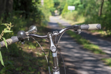 Turystyczny ( trekingowy)  rower na leśnej drodze widoczna kierownica i stalowa rowerowa trąbka .  - obrazy, fototapety, plakaty