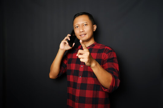 Adult man showing happy expression with finger pointing up when holding mobile phone