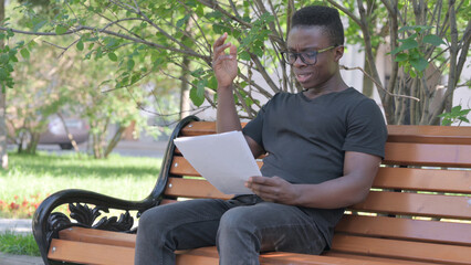 Young African Man Feeling Upset while Reading Contract Outdoor