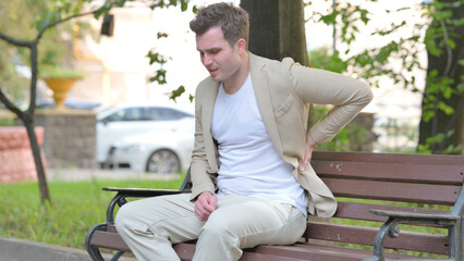 Obraz premium Casual Young Man Sitting Outdoor with Back Pain