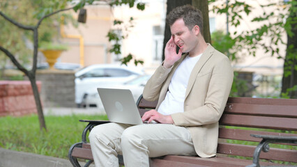 Casual Young Man with Headache Working on Laptop Outdoor