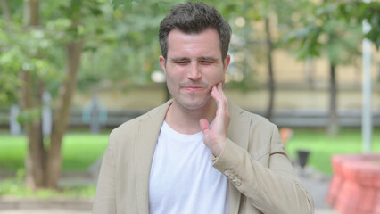 Outdoor Portrait of Casual Young Man with Toothache