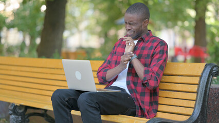 Fototapeta premium Young African Man with Wrist Pain Working on Laptop Outdoor