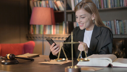 Female Lawyer Celebrating Win on Smartphone in Office