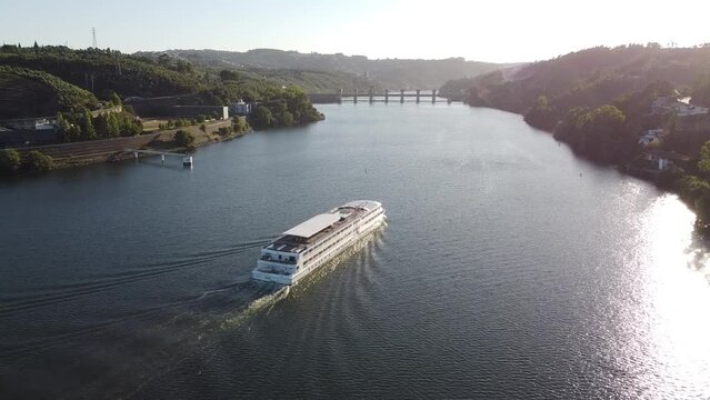 Cruise ship travel the waters of the Douro River, with the Crestuma dam in background. Portugal, 2023