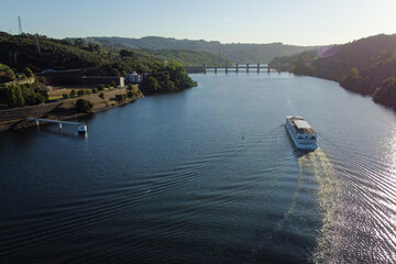Cruise ship travel the waters of the Douro River, with the Crestuma dam in background. Portugal, 2023