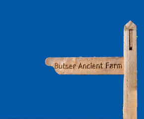 Rustic wooden signpost showing the way to Butser Ancient farm in Hampshire, UK